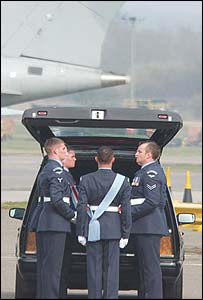 Members of the RAF places one of their number into a hearse from an RAF transport plane