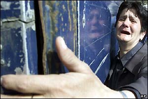 A Bosnian Muslim woman refugee from Srebrenica area who lost her sons weeps as she touches a truck loaded with identified mortal remains of 300 Srebrenica massacre victims