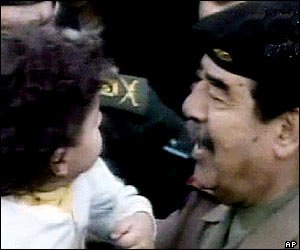 Saddam Hussein holds up a young Iraqi girl in the crowd
