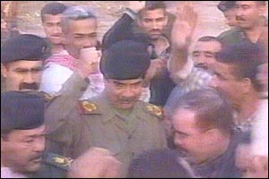 Iraqi TV picture showing Saddam Hussein raising his fist while surrounded by guards
