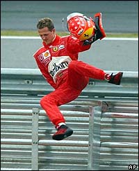 Ferrari's Michael Schumacher leaps over a safety barrier after retiring from the race
