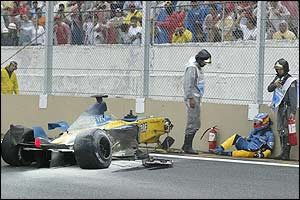 Fernando Alonso sits injured at trackside after crashing into debris