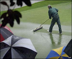 A greenkeeper at Augusta clears water from a green after heavy rain