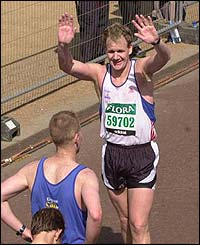 Chef and restaurant owner Gordon Ramsay holds his hand up in joy after finishing the race