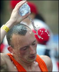A competitor keeps cool by tipping water onto his head 