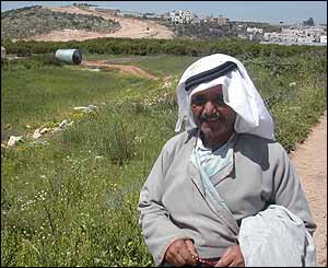 Palestinian farmer with excavation and the town of Izbat Suleiman in the background