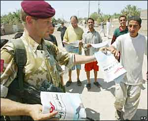 An officer of 1st Battalion The Parachute Regiment, distributes newspapers to Iraqi people in al Qurna, Iraq