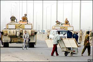 Iraqis pass by British tanks in the Iraqi southern city of Basra 