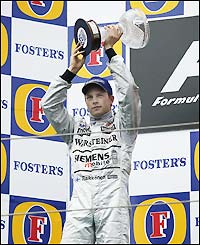 McLaren's Kimi Raikkonen lifts his trophy after finishing second