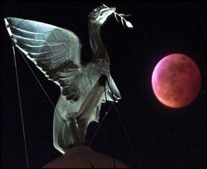 Partially-eclipsed red moon seen adjacent to a Liver Bird atop the Liver Buildings in Liverpool