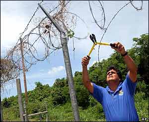 Fernando Nunuez of US Fish and Wildlife Service cuts down navy fence 