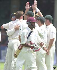 Daren Ganga (foreground) leaves the pitch as Australia celebrate taking his wicket for just six