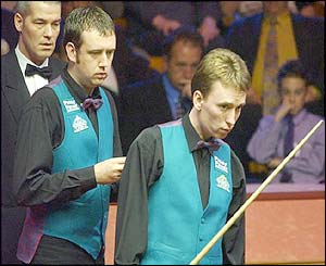 Mark Williams and Ken Doherty stand over the table as the match referee looks on