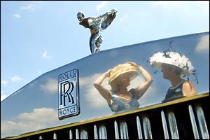 Ladies adjusting their hats are reflected in the shiny front of a Rolls Royce