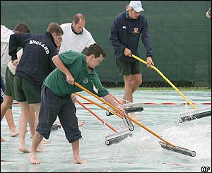 Ground staff mop the covers to get ready for Sunday's practice