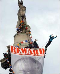 Professional stuntman Gary Connery leaps off the column as the other protesters unfurl a banner
