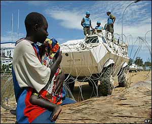 A young boy holds a child in front of the UN compound 