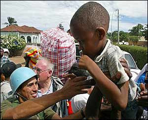 A UN soldier lifts a boy onto a truck to be evacuated out of the area