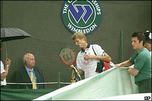 Alexander Popp leaves Court One as rain falls at SW19