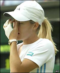 Justine Henin-Hardenne holds her face as she contemplates losing to Serena Williams