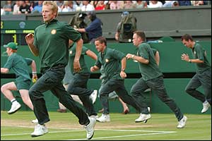 The ground staff run onto Centre Court to pull the covers on