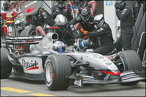David Coulthard gets stuck in the pits as a fuel hose gets jammed