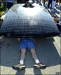 Student's legs are visible as he works underneath a car 