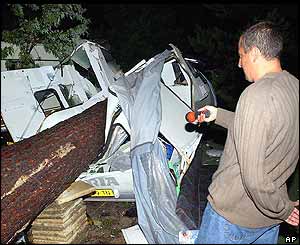 A man looks at a trailer destroyed by a fallen tree at the La Rive campground near Biscarosse