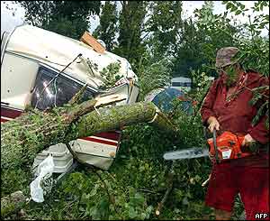 A camper clears his caravan from branches with a chainsaw at the Gennes campsite, central France