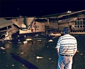 A driver looks at his damaged truck under a part of the roof of the Air France office in the freight zone near Bordeaux airport