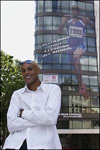 French 400m runner Marc Raquil poses in front of the official poster for the 2003 World Athletics Championships