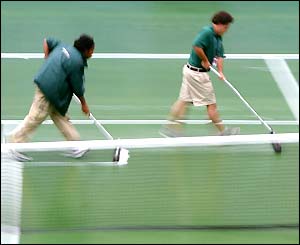 Attendants sweep water off of the Arthur Ashe court at Flushing Meadows