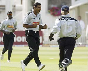 Warwickshire's Waqar Younis celebrates with Trevor Penney after taking the wicket of Virender Sehwag