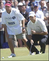 Retief Goosen's caddy helps his man line up a putt