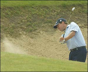 Davis Love III grimaces as he hits out of a bunker