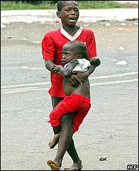 A boy carrying his young brother flees the mortar attack near the US embassy in Monrovia