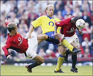 Fortune and Neville tackle Arsenal's Dennis Bergkamp