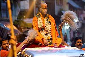 Devotees fan priest on car roof