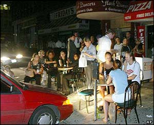Patrons eat outside Leon's Pizza in Manhattan, under the lights of a parked car