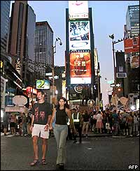 A couple walks across the street in Times Square in New York 15 August 2003 as power returned to the city