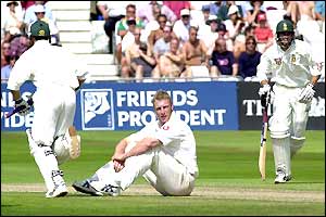 Andrew Flintoff sits on the turf as Neil McKenzie and Mark Boucher go for a run