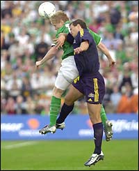 Damien Duff jumps for the ball with Australia's Lucas Neill