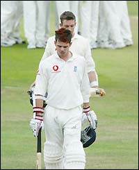 A dejected Jimmy Anderson walks off the field 
