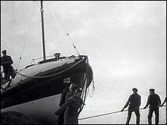 People pulling on ropes to launch lifeboat