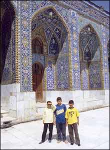 Three boys standing outside mosque in Kerbala, Iraq