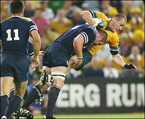 Australia's Stirling Mortlock is hit by a strong tackle from Scotland