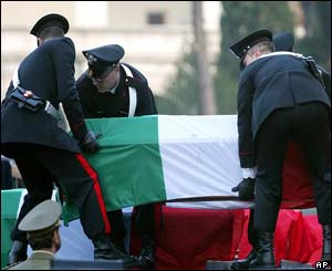 Italian Carabinieri officers place one of the 19 caskets, covered in the Italian flag, on an army truck to be taken to St Paul Basilica 