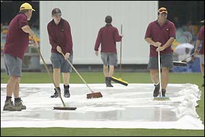 Groundsmen desperately try to mop up surface water at the Gabba 