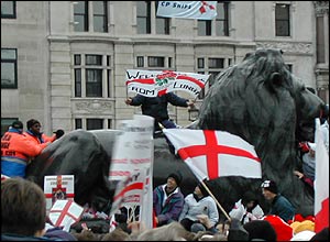 Guards try to coax fan off lion statue