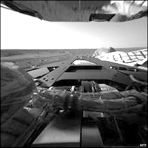 The first pictures, taken by the hazard avoidance camera on the Rover Spirit, show the rover's rear lander petal and, in the background, the Martian horizon..